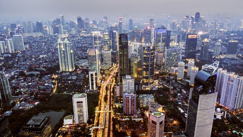 Aerial view of illuminated buildings in city against sky