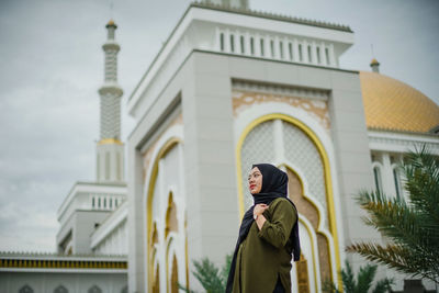 A veiled woman against the background of the great mosque of al-falah mempawah. 