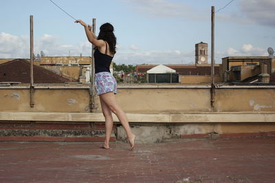 Woman with arms raised standing against sky