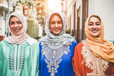 Portrait of smiling three women wearing headscarf while standing outdoors