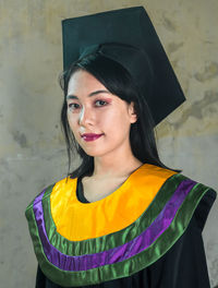 Portrait of a smiling young woman standing against wall