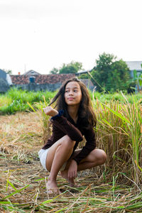 Portrait of smiling young woman sitting on rice field.