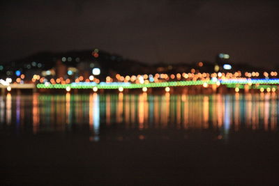 Defocused image of illuminated city by river at night