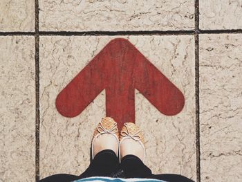 Low section of woman standing arrow sign