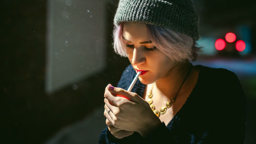 Close-up of young woman lighting cigarette