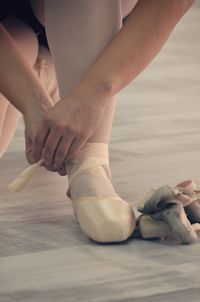 Low section of woman wearing ballet shoe at studio