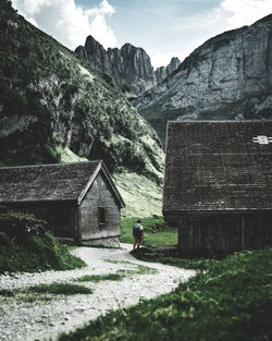 Man walking on country road amidst houses and mountains