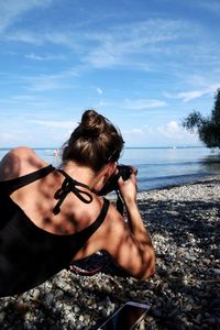 Young woman photographing sea through sunglasses