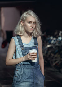 Portrait of young woman having coffee while standing outdoors