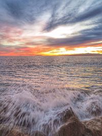 Scenic view of sea against cloudy sky during sunset