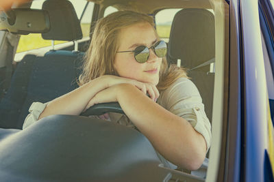 Portrait of young woman sitting in car