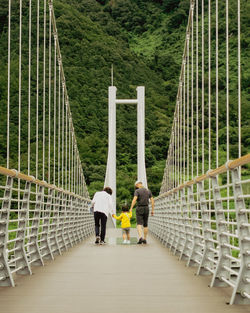 Rear view of people walking on footbridge