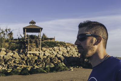 Side view of young man wearing sunglasses at beach