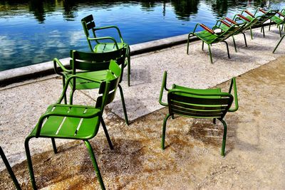 Empty chairs on grass by water