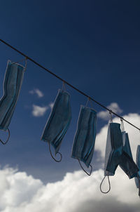 Low angle view shot of masks hanging on clothesline against sky
