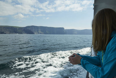 Side view of woman standing in boat against sky