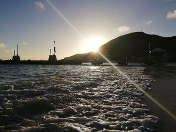 Sea by buildings against sky during sunset