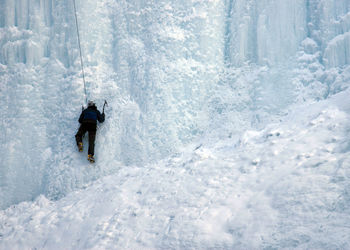 Rear view of person climbing wall of ice