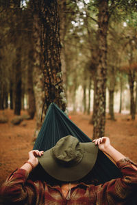 Midsection of woman with umbrella against trees in forest