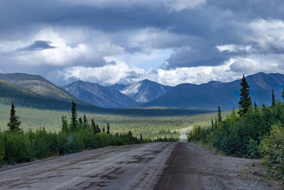 Empty road along landscape and mountains against sky