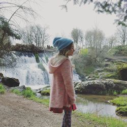 Rear view of girl standing by river against sky