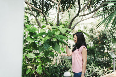 Side view of woman standing against plants