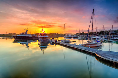 Sailboats moored at harbor during sunset