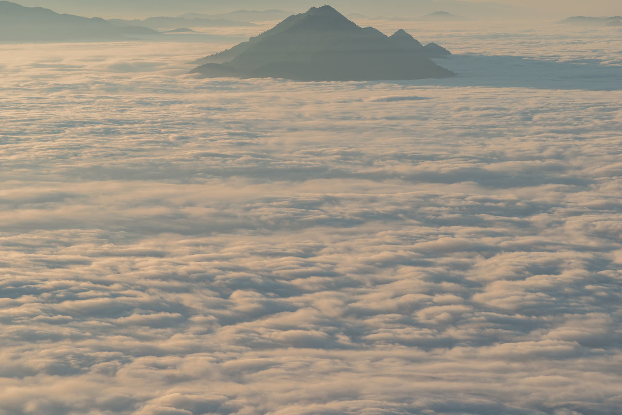 AERIAL VIEW OF CLOUDS OVER LAND AND MOUNTAINS