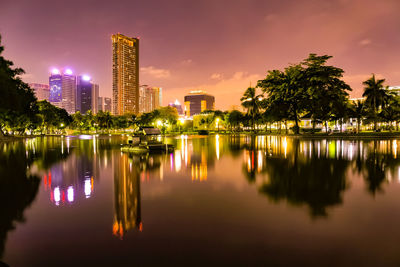 Scenic view of lake by buildings against sky at night