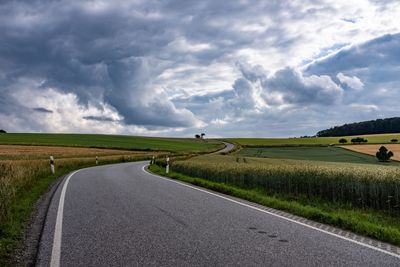 Road amidst field against sky