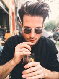 Close-up of a young man sipping drink outdoors