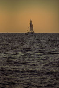 Sailboat sailing on sea against sky during sunset