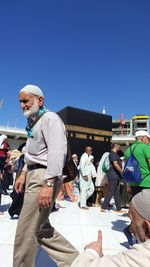 People standing by building against clear blue sky