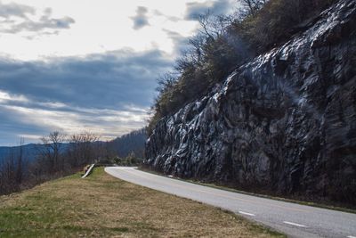 Road by cliff against sky