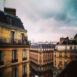 Buildings in city against cloudy sky