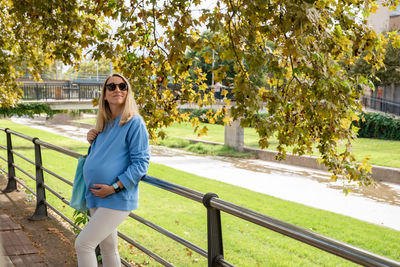 Pregnant girl in a blue hoodie against the backdrop of an autumn landscape