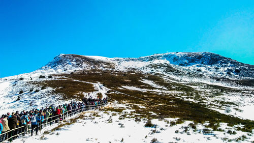 Low angle view of snowcapped mountain against clear blue sky