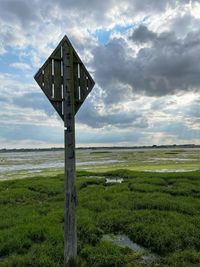 Wooden post on field against sky