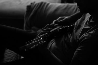 Midsection of man playing guitar in darkroom