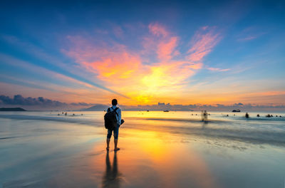 Man standing on beach against sky during sunset