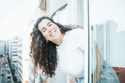 Portrait of smiling woman leaning out of window