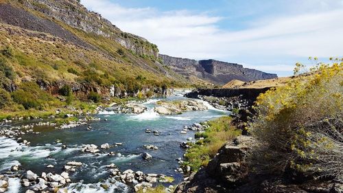 Scenic view of river by mountains against sky