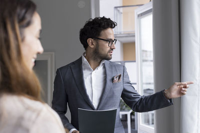 Male real estate agent pointing while talking with female client at home