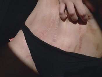 Close-up of person hand with tattoo on black background