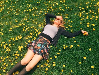 High angle view of beautiful woman resting on field surrounded by yellow flowers