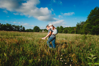 Full length of man daughter while walking on field against sky