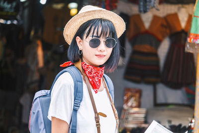 Portrait of young woman wearing hat and sunglasses in city