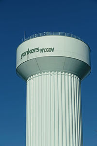 Low angle view of water tower against clear blue sky