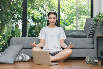 Young woman sitting on sofa at home