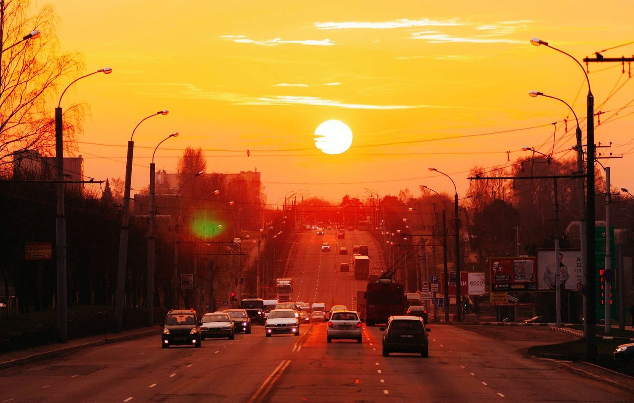 sunset, transportation, car, land vehicle, mode of transport, city, building exterior, street, street light, road, orange color, architecture, built structure, sky, sun, traffic, city street, the way forward, city life, on the move